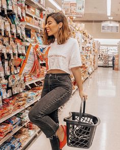 a woman holding a shopping basket while standing in a grocery store aisle with her feet on the ground