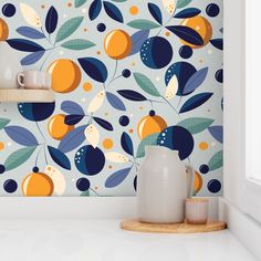 an orange and blue wallpaper in a kitchen with white counter tops, pots and cups on the shelf