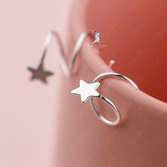 These gorgeous, delicate star hoop earrings are crafted from pure 925 sterling silver and feature a polished finish for a stunning shine. The intricate spiral design ensures that they are comfortable for daily wear and can easily elevate any outfit. Add these charming star spiral hoops to your everyday collection or gift them to a loved one. Materials: 925 sterling silverFinish: gold plate, platinum plate Jewelry Care: See more information about how to care for your jewelry here. Shipping Policy Silver Spiral Ear Cuff, Silver Star-shaped Ear Cuff As Gift, Silver Star Shaped Ear Cuff As Gift, Silver Star Shaped Ear Cuff Gift, Silver Star-shaped Ear Cuff For Gift, Sterling Silver Star Cartilage Earring, Sterling Silver Cartilage Earrings With Star Charm, Dainty Sterling Silver Star Hoop Earrings, Ear Huggies