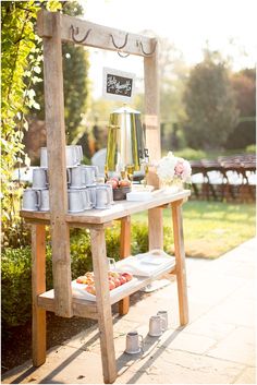 an outdoor table with food and drinks on it in the middle of a garden area