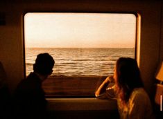 two people are looking out the window at the ocean