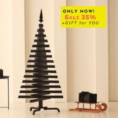 a black christmas tree sitting on top of a white floor next to a wooden sled