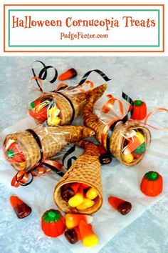 some candy wrapped in plastic bags on top of a white table with pumpkins and candies