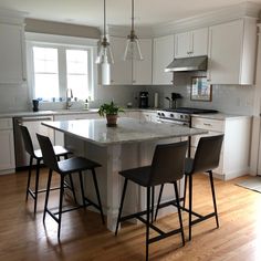 a kitchen with white cabinets and an island in the middle, surrounded by bar stools