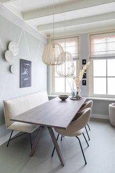 a dining room table and chairs in front of a window with hanging lights on the wall