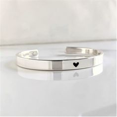 "* DETAILS:  - one .925 Solid Sterling 1/4\" x 6\", 6.5\", 7\", 7.5\" or 8\" cuff bracelet with a small heart engraved on the center - inside text, 50 characters or less - all cuffs can be adjusted with slight pressure to be made tighter or looser » DON'T FORGET TO GRAB A SUNSHINE POLISHING CLOTH: https://www.etsy.com/listing/469627127/sunshine-cleaning-cloth-for-jewelry?ref=shop_home_active_1 » CHECK OUT MY ENTIRE SHOP https://www.etsy.com/shop/TatumBradleyCo?ref=si_shop » My Shop Feedback: https://www.etsy.com/your/shops/TatumBradleyCo/reviews?ref=shop_info" Adjustable Silver Cuff Bracelet For Promise, Classic Heart-shaped Bracelets With Polished Finish, Classic Heart-shaped Sterling Silver Bracelet, Classic Sterling Silver Heart Bracelet For Valentine's Day, Stackable Sterling Silver Bracelet For Anniversary, Silver Sterling Silver Bracelets For Promise, Silver Bangle Bracelets For Promise, Modern Adjustable Jewelry For Valentine's Day, Silver Hand Stamped Cuff Bracelet As A Gift