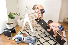 two children are playing on a bed made out of wood and metal, while another child is wearing diapers