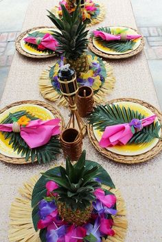 the table is set with pineapples, flowers and other tropical decorations on it