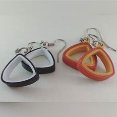 two pairs of earrings made out of wood and leather are shown on a white surface