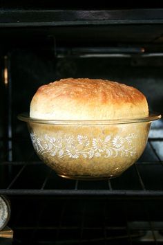 a loaf of bread sitting in an oven on top of a glass dish with floral designs