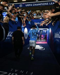 a man walking down a blue carpet covered in lots of people holding up their hands