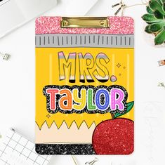 a clipboard with the words mrs taylor on it and an apple next to it