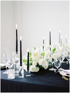 the table is set with white flowers and black candles