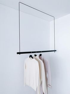 two shirts hanging on a clothes rail in front of a mirror with black bar and hangers