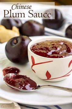 plum sauce in a white bowl with spoons on a plate next to plums