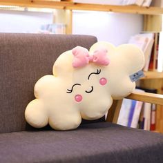 a pillow shaped like a cloud with a pink bow on it sitting on a chair