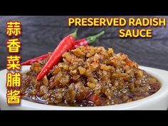 a bowl filled with cooked radish sauce and two red peppers on the side