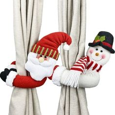 two stuffed snowmen hanging from the side of curtains