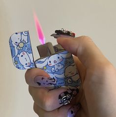 a person holding a lighter in their hand with the lighter lit up and cartoon designs on it