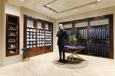 a mannequin is standing in front of a display of shirts and shoes at a clothing store