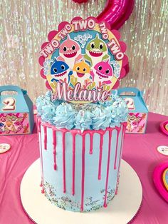 a birthday cake with pink icing and decorations on the top is sitting on a table