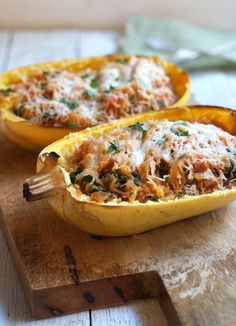 two stuffed squash halves on a wooden cutting board with a fork in one side and another half filled with food