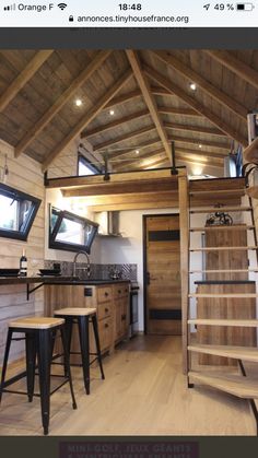 a kitchen with wooden floors and stairs leading up to the upper floor, along with two stools