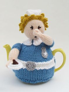 a knitted doll sitting in a teapot with its mouth open and hands on her chin