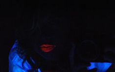 a woman in the dark holding her cell phone up to her face with glowing blue light