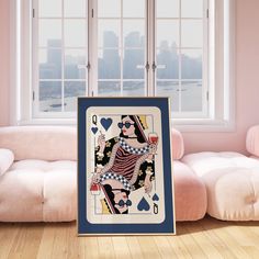 a playing card sitting on top of a wooden floor in front of a pink couch