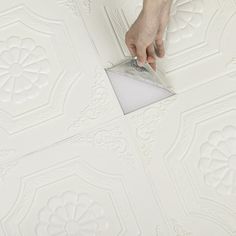 a person is painting the ceiling with white paint on it and there is a small square piece of paper in front of them