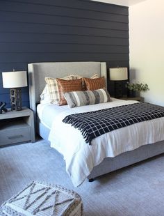 a bedroom with a bed, nightstands and two lamps on either side of the bed