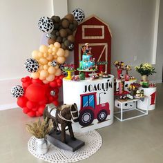 a birthday party with balloons, decorations and farm animals on the table in front of it