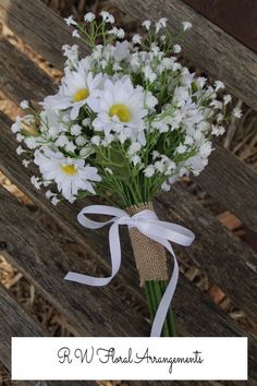 a bouquet of daisies tied to a wooden bench