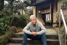 an older man sitting on steps in front of a house