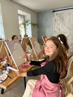 a woman sitting at a table with easels in front of her