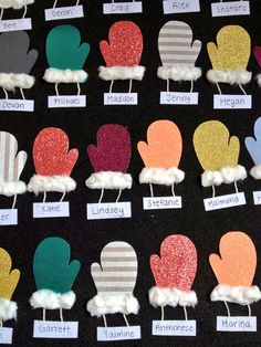 there are many different colored mittens on the black tablecloth with name tags attached to them