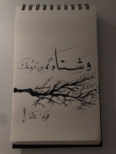 a spiral notebook with arabic writing on the cover and an image of a tree branch