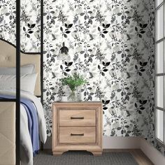 a bedroom with a bed, nightstand and wallpaper in black and white color scheme