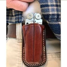 a person holding a leather case with two scissors in it