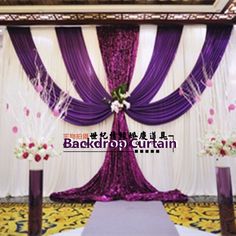 a purple and white stage set up for a wedding ceremony with flowers on the floor