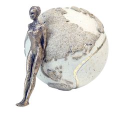 a silver statue is standing next to a white ball that has been cracked in half