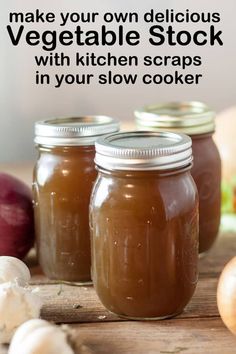 three jars filled with brown liquid sitting on top of a wooden table next to onions and garlic