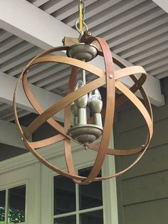 a wooden chandelier hanging from the ceiling in front of a house with windows