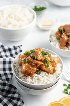 two bowls filled with chicken and rice on top of a table next to orange slices