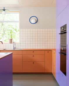 an orange and purple kitchen is shown in this image