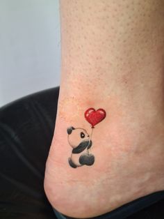 a small tattoo on the ankle of a girl with a panda bear holding a heart shaped balloon