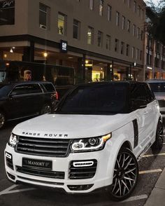 a range rover is parked on the street in front of a building with cars behind it