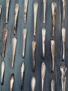 an assortment of silver objects are displayed on a wooden surface, including spoons and forks