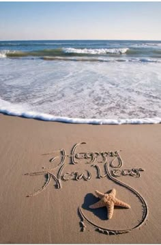 a happy new year written in the sand with a starfish on it's side